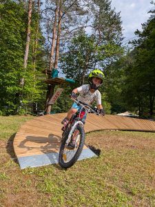 Otrok se vozi po lesenem pumptracku v Pustolovskem parku NOD Završnica.