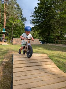 Otrok na poganjalčku vozi po lesenem pumptracku v Završnici.