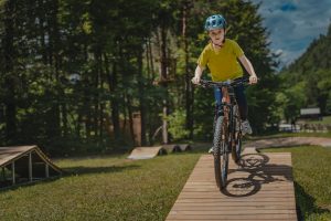 Otrok vozi po lesenem pumptracku v Pustolovskem parku NOD Završnica.