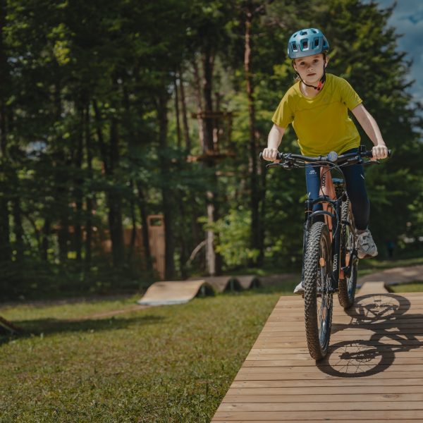 Otrok vozi po lesenem pumptracku v Pustolovskem parku NOD Završnica 